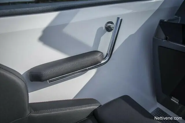 Interior image of a boat door featuring a chrome grab handle and black cushioned armrest, with a hint of shadow.